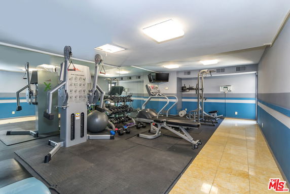Indoor gym area with various exercise equipment and mirrored walls
