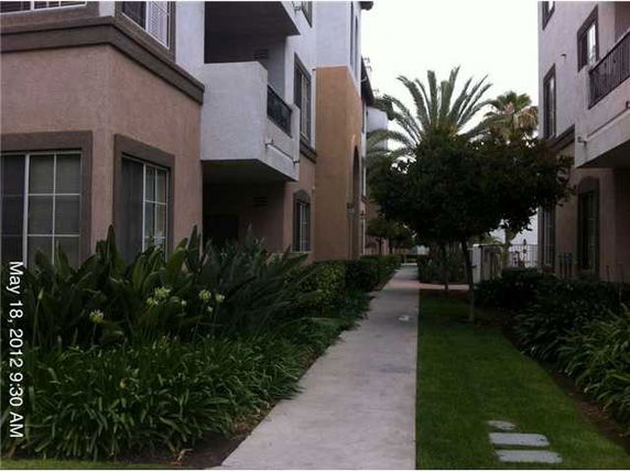 Front view of a multi-story residential building with balconies and landscaped pathway.
