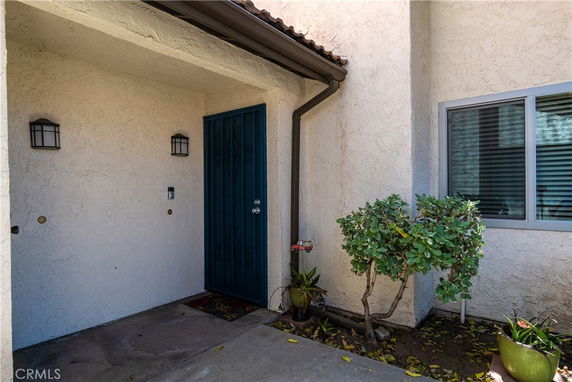 Front view of a house entrance with a blue door and outdoor lights.