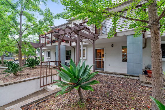 Front view of a two-story house with a balcony and pergola.
