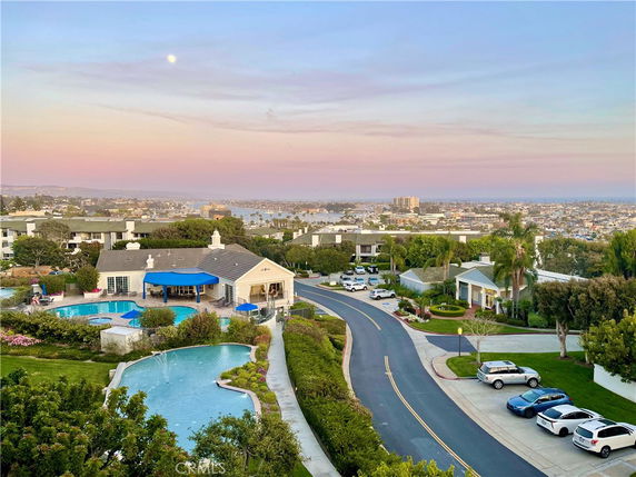 Panoramic view of a residential area with a swimming pool and distant cityscape.