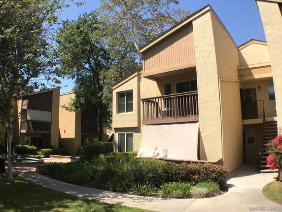 Front view of an apartment building with a balcony and multiple windows.