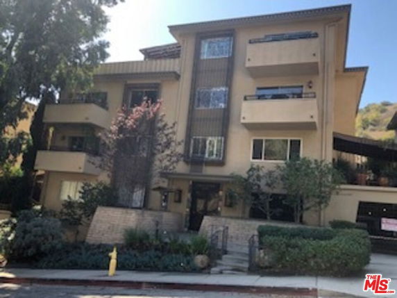 Front view of a multi-story building with balconies and large windows.