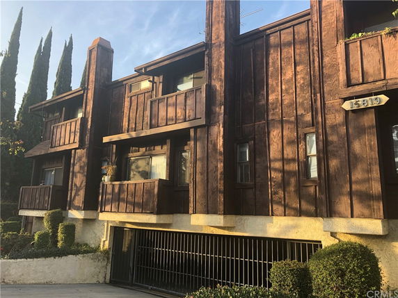 Front view of a multi-story building with wooden exterior and balconies.