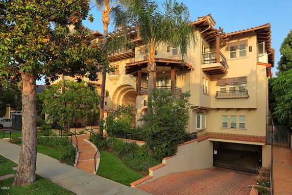 Front view of a multi-story house with a driveway and balconies.