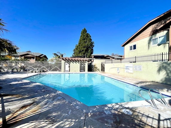 Outdoor swimming pool with surrounding fence and buildings.