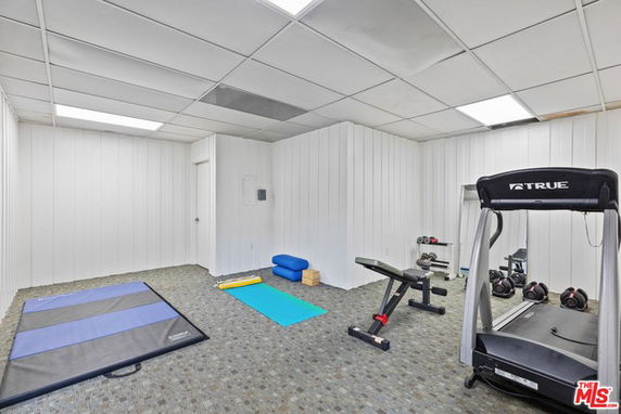 Indoor gym area with workout mats, treadmill, bench, and dumbbells.