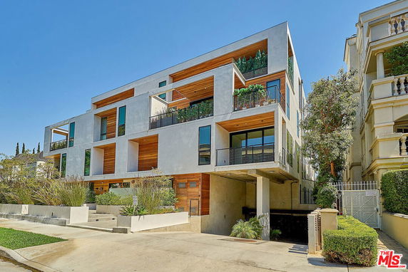 Front view of a modern multi-story building with large windows and balconies.