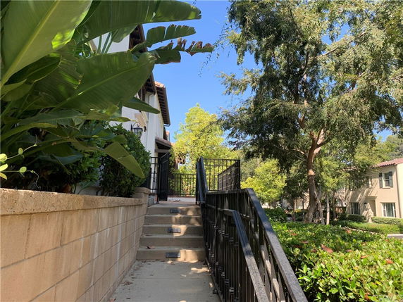 Side view of a building with stairs and railing leading to an elevated entrance.