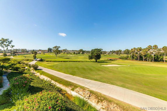 Panoramic view of a golf course with lush greenery and a clear blue sky.