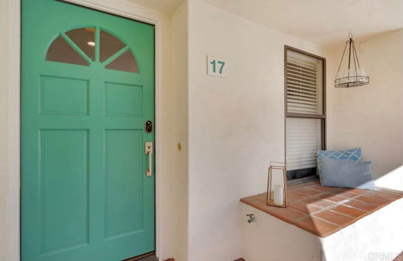 Front entrance area of a house with a teal door and a small seating nook.