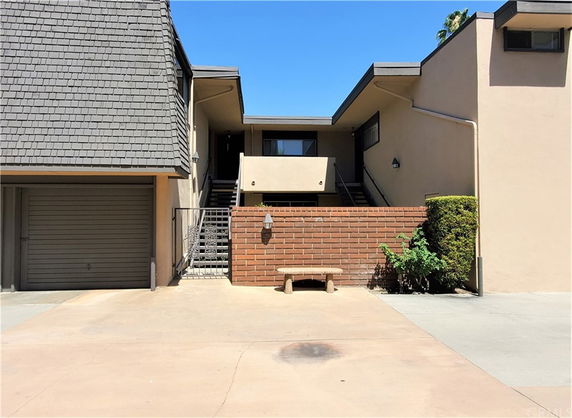 Front view of a two-story building with a garage and brick wall.
