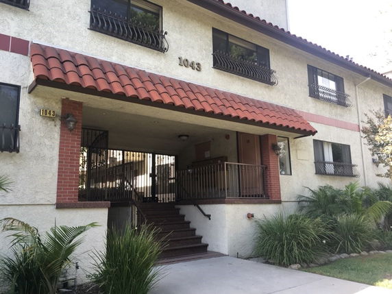 Front view of a two-story building with tiled roof and metal window grilles.