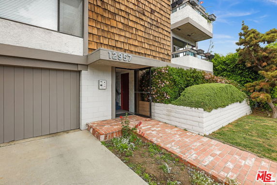 Front view of a building with a brick walkway and shingle siding.