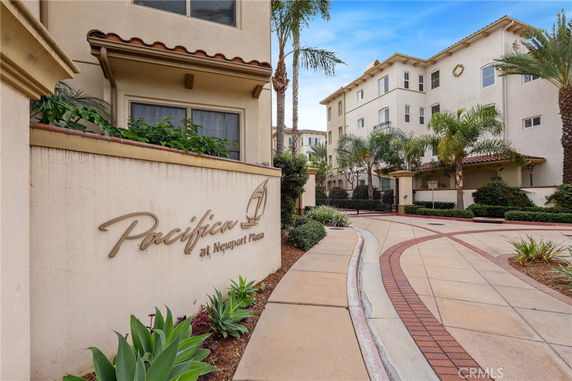 Front view of a multi-story residential building with a paved walkway and landscaped area.