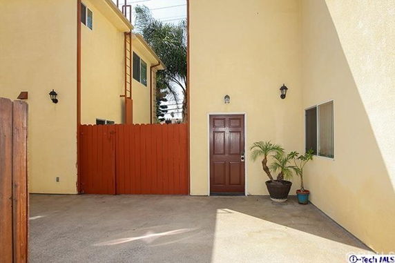 Front view of a building entrance with a red door and fencing.