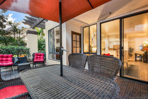 Outdoor patio area with wicker furniture and large windows leading to the indoor space.