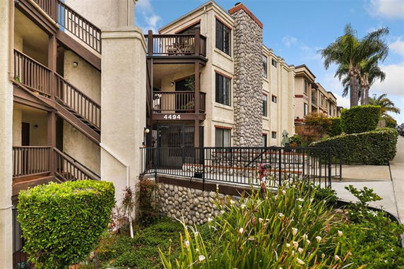 Front view of a multi-story residential building with stone accents and balconies.