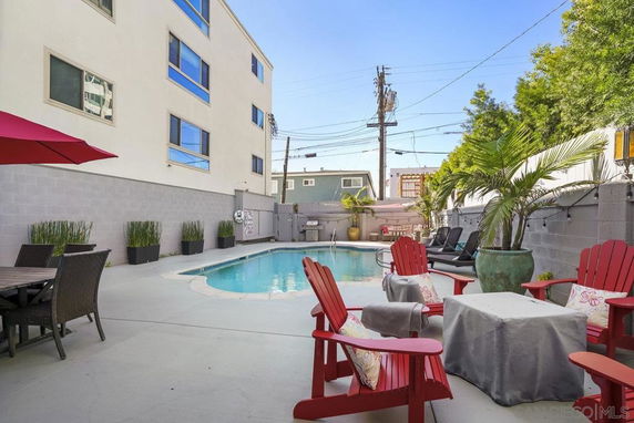 Outdoor swimming pool area with surrounding seating and potted plants.