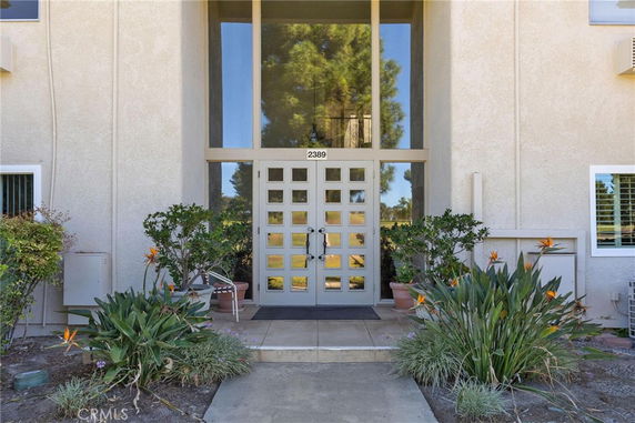 Front view of a beige building entrance with large windows and a decorative door.