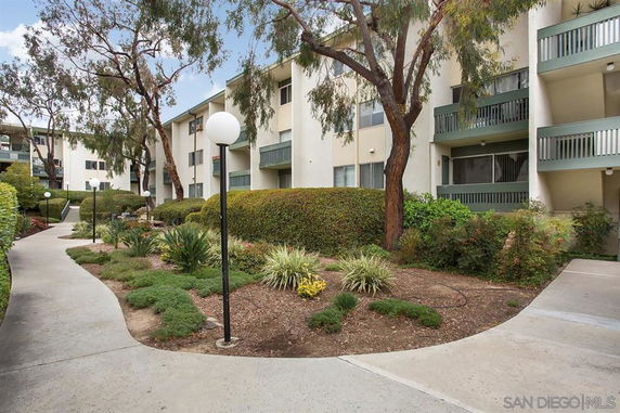 Front view of a multi-story apartment building with balconies and landscaped walkways.