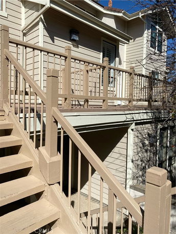 Front view of a two-story house with beige wooden railing and stairs.