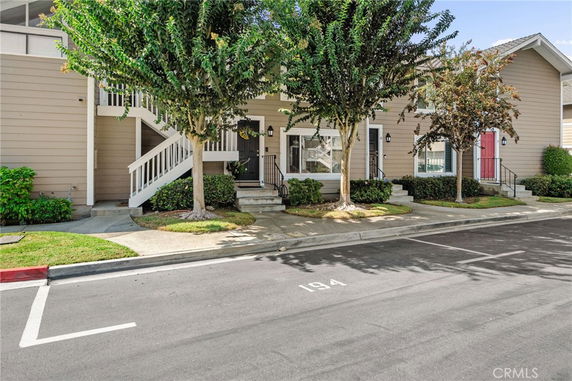 Front view of a two-story residential building with stairs and parking space.