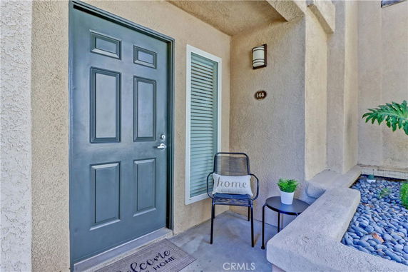 Front entrance of a house with a gray door and a small seating area.