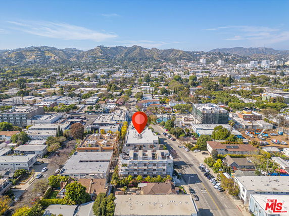 Aerial view of a cityscape with multiple buildings and mountains in the background.