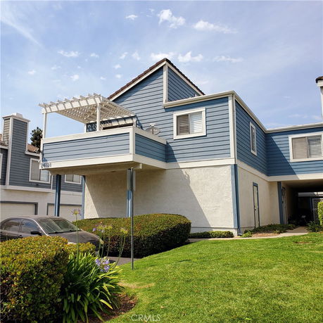 Front view of a two-story house with a balcony and blue siding.