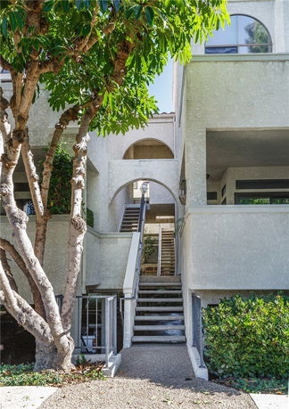 Front view of a multi-level building with arched entrances and exterior stairs.