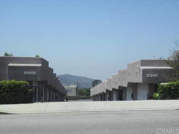 Front view of a row of single-story buildings with uniform design and garage doors.