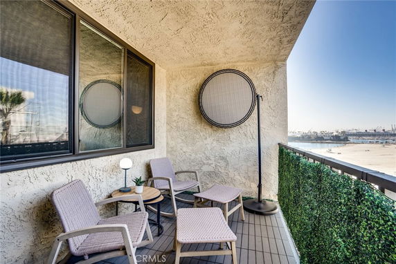 Balcony with chairs, table, and a distant view of the water and port.