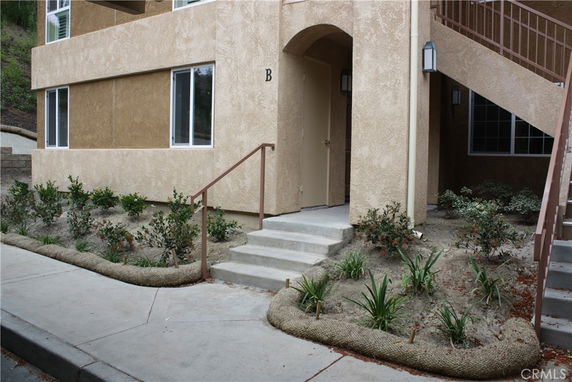 Front view of a building entrance with stairs and brown stucco exterior.