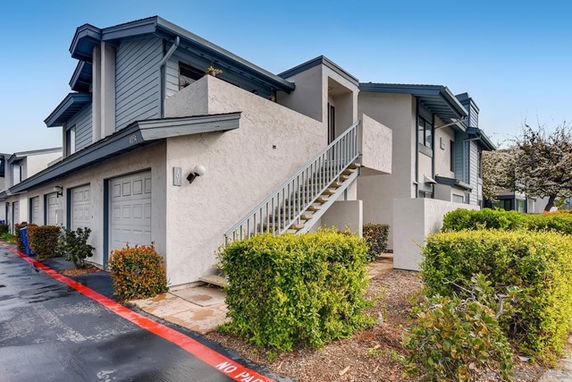 Front view of a multi-story residential building with external staircases and garages.