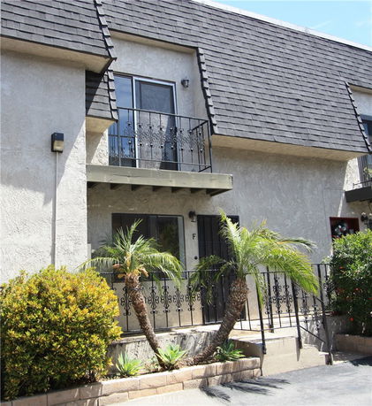 Front view of a multi-story building with balconies and a tiled roof.