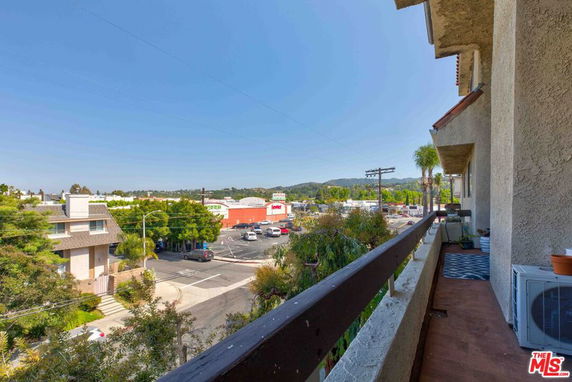 View from a building showing a street, houses, and distant hills.