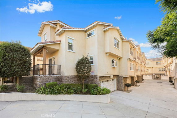 Front view of a multi-story residential building with a beige exterior and decorative stone accents.