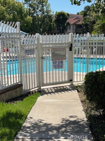 Outdoor swimming pool surrounded by a white metal fence.