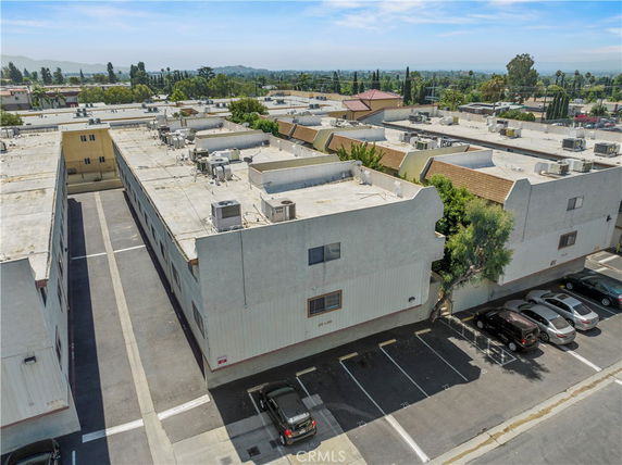Rooftop view of a building with multiple air conditioning units and parking area visible.