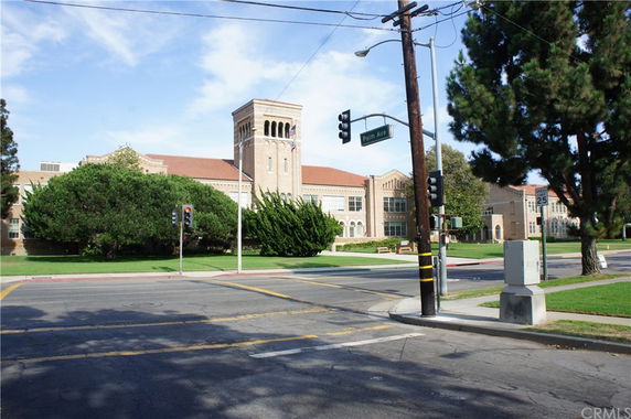 Front view of a large brick building with a tower and surrounding trees.