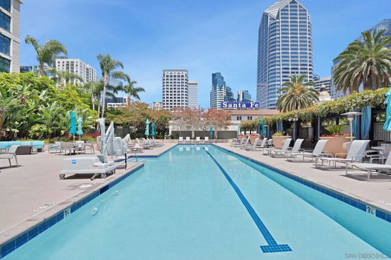 Outdoor swimming pool area with high-rise buildings in the background.