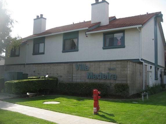 Front view of a two-story building with chimneys and a red-tiled roof.
