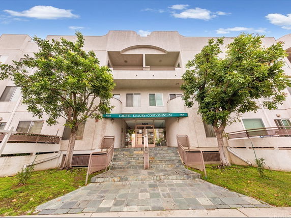 Front view of a condominium building with a central entrance and two balconies.