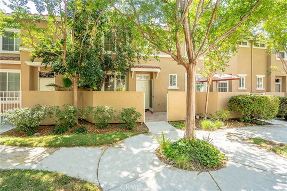 Front view of a two-story townhouse with a small porch and trees.