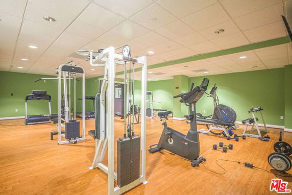 Indoor gym area with exercise equipment and green walls.
