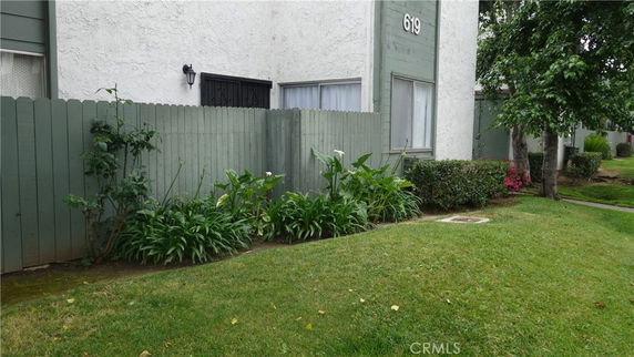 Exterior view of a building corner with a green fence and grassy area.