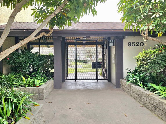 Front view of a building entrance with gate and greenery.
