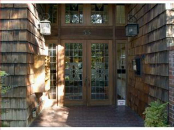 Front view of a building entrance with wooden doors and decorative glass panels.