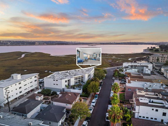 Aerial view of a residential area with buildings near a body of water at sunset.
